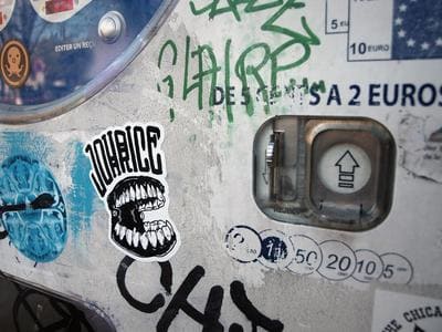 Parcmètre urbain couvert de graffitis et autocollants.