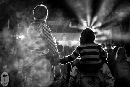 Enfants sur épaules en foule lors d'un événement nocturne