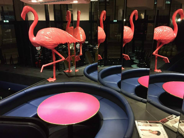 Décoration intérieure avec flamants roses et tables rondes roses reflétées dans un miroir pour la marque We Are Juice