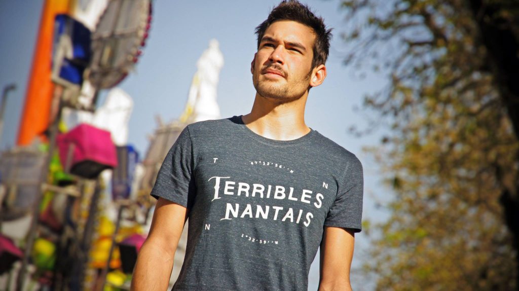 Homme portant un t-shirt avec un message imprimé devant la ville de Nantes
