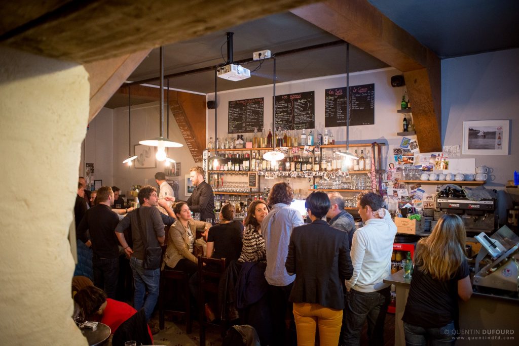 Groupe de personnes se réunissant dans un bar animé avec un comptoir de bar en arrière-plan pour l'évènement Movember