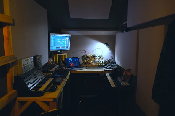 Studio de musique éclairé avec du matériel électronique et un ordinateur affichant des logiciels audio