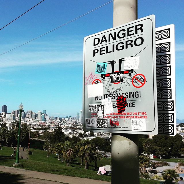 Panneau d'avertissement couvert de multiples autocollants personnalisés dont certain sont des stickers EYE, dans la ville de San Francisco