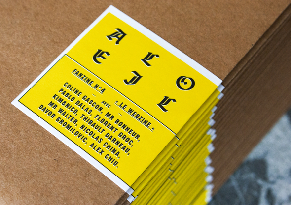 Pile de fanzine imprimés avec une couverture jaune avec textes et graphiques noirs empilés sur une surface