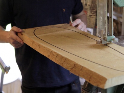 Artisan découpant du skateboard à la scie dans un atelier