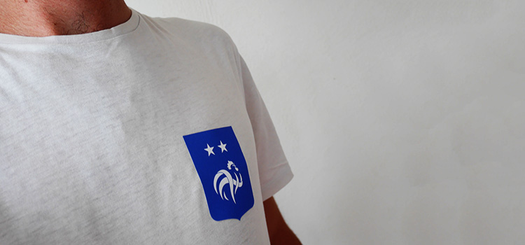 sticker textile personnalisé avec un logo de l'équiê de france de football collé sur le coeur d'un t-shirt blanc chiné